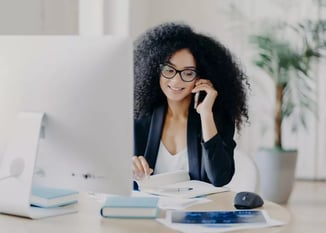 Woman sitting at laptop talking on phone